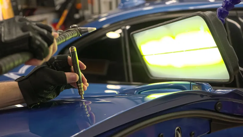 auto body technician using special tools to for dent repair